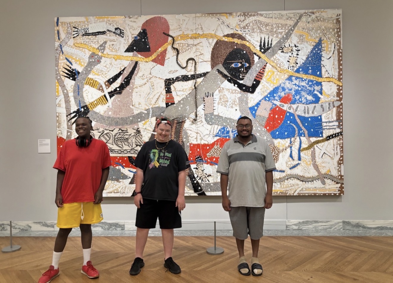 Three people enjoying a museum visit in front of a colorful artwork